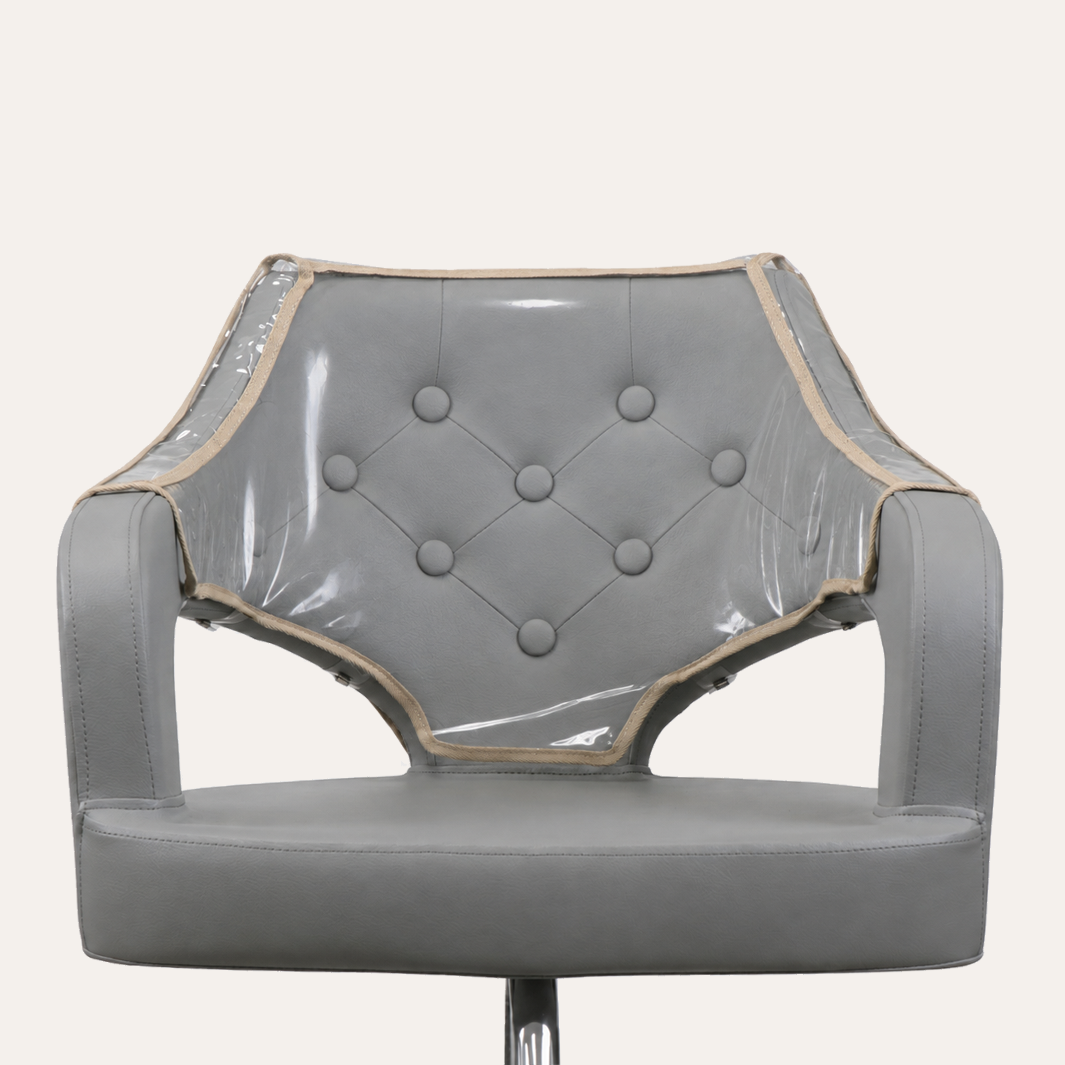 A gray upholstered chair with a clear vinyl protective cover draped over the backrest