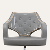 A gray upholstered chair with a clear vinyl protective cover draped over the backrest