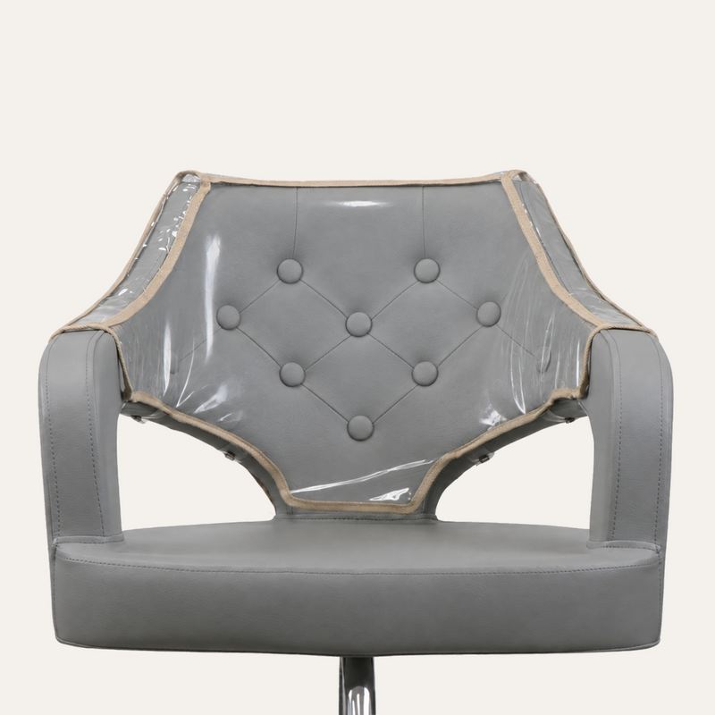 A gray upholstered chair with a clear vinyl protective cover draped over the backrest