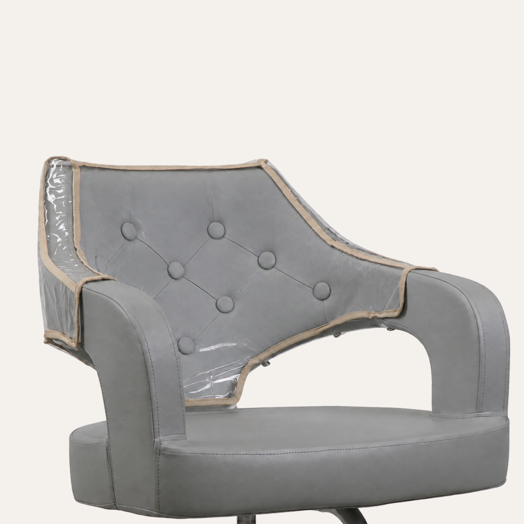 A gray upholstered chair with a clear vinyl protective cover draped over the backrest